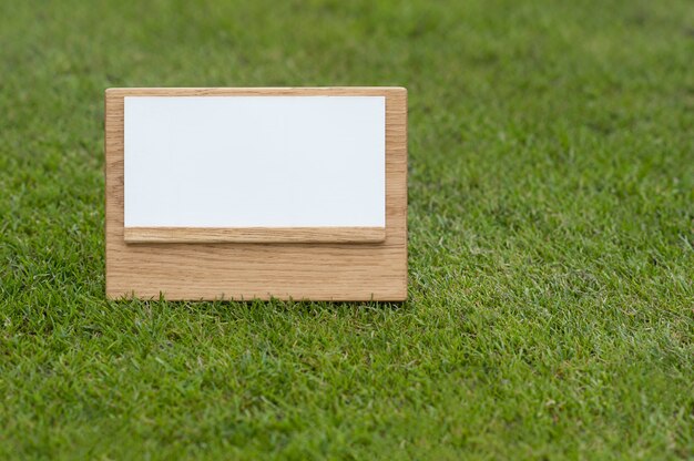 Photo mock up wooden sign on green background.