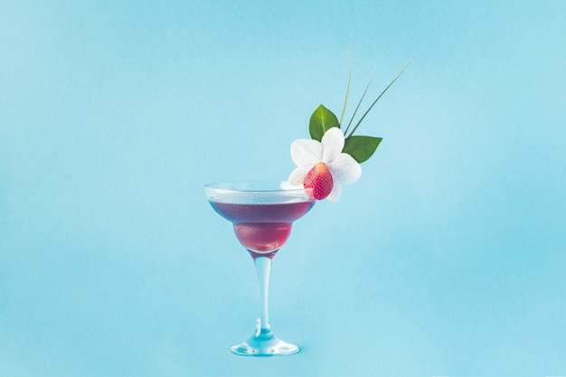 Mocktail versierd met aardbeien, bloemen en tropische bladeren, selectieve aandacht.