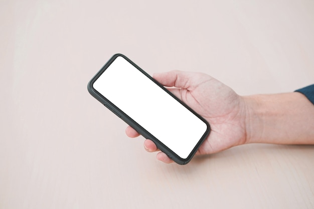 Mockup afbeelding leeg scherm smartphone. lege witte smartphone gehouden door mannenhand op houten achtergrond.