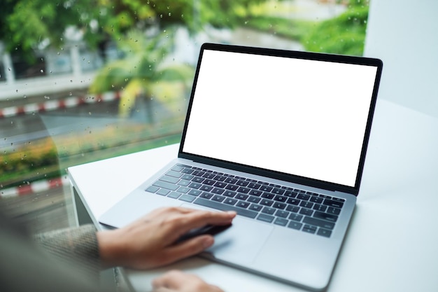 Mockup-afbeelding van een hand die het touchpad van een laptopcomputer gebruikt en aanraakt met een leeg wit bureaubladscherm