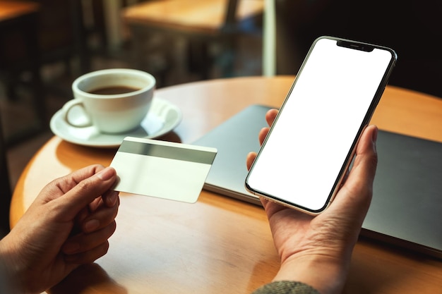 Mockup-afbeelding van een handen met een creditcard en een mobiele telefoon met een leeg desktopscherm op kantoor