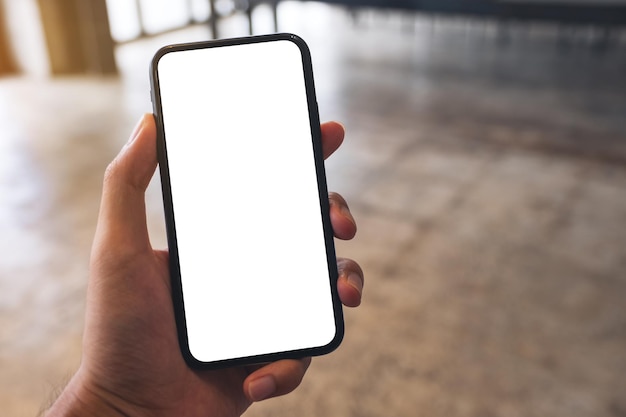 Mockup-afbeelding van een man met een zwarte mobiele telefoon met een leeg wit scherm in café