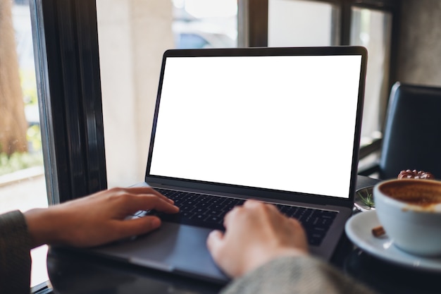 Mockup-afbeelding van een vrouw die een laptop gebruikt en typt met een leeg wit desktopscherm in café