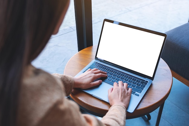 Mockup-afbeelding van een vrouw die een laptop gebruikt en typt met een leeg wit desktopscherm in café