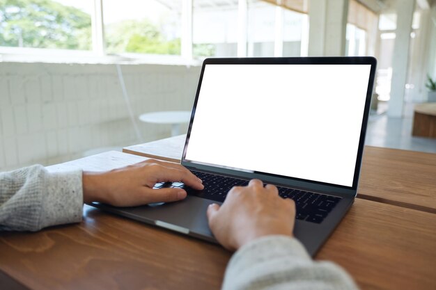 Mockup-afbeelding van een vrouw die gebruikt en typt op het toetsenbord van een laptopcomputer met een leeg wit desktopscherm op houten tafel