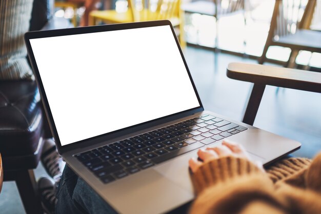 Foto mockup-afbeelding van een vrouw die het touchpad van een laptop gebruikt en aanraakt met een leeg wit desktopscherm