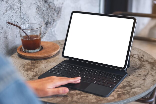 Mockup-afbeelding van een vrouw die het touchpad van een tablet aanraakt met een leeg wit bureaubladscherm als een computer-pc op tafel