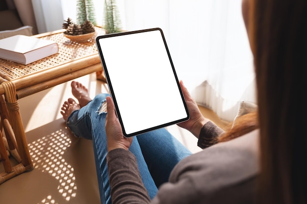 Mockup-afbeelding van een vrouw die thuis een tablet-pc vasthoudt en gebruikt met een leeg desktop-wit scherm