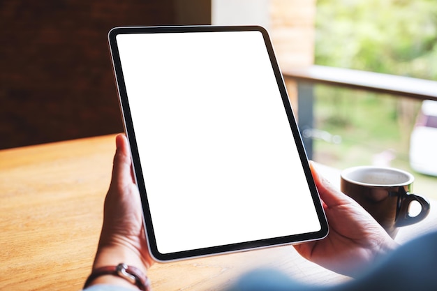 Mockup-afbeelding van een vrouw met een digitale tablet met een leeg wit bureaubladscherm in café