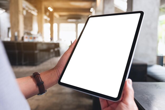Mockup-afbeelding van een vrouw met een digitale tablet met een leeg wit bureaubladscherm in café