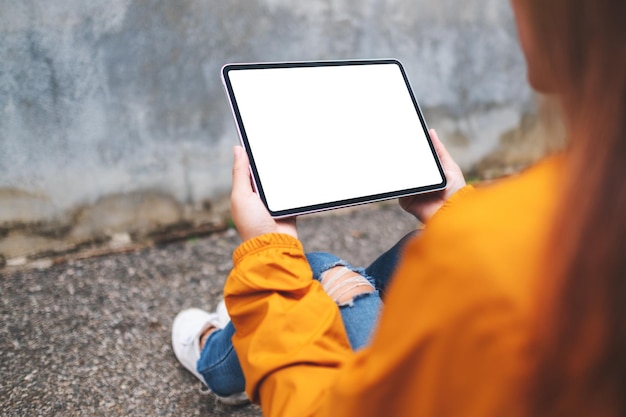 Mockup-afbeelding van een vrouw met een digitale tablet met een leeg wit bureaubladscherm in de buitenlucht