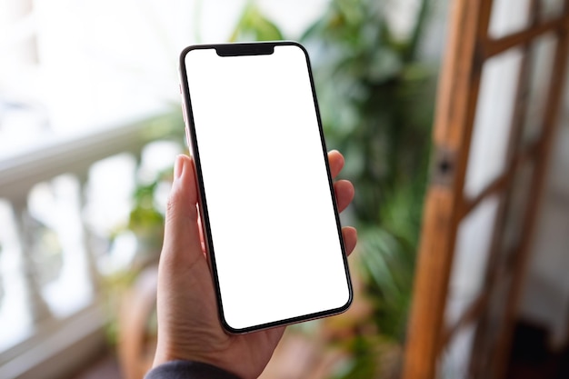 Mockup-afbeelding van een vrouw met een mobiele telefoon met een leeg desktopscherm op het balkon thuis