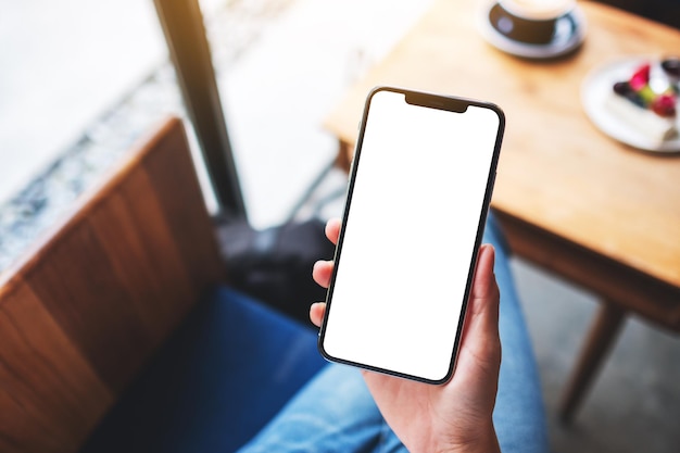 Mockup-afbeelding van een vrouw met een mobiele telefoon met een leeg wit desktopscherm in café