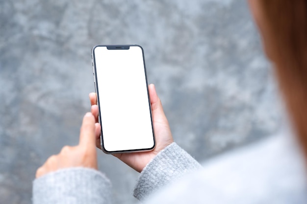 Mockup-afbeelding van een vrouw met een mobiele telefoon met een leeg wit desktopscherm in de buitenlucht