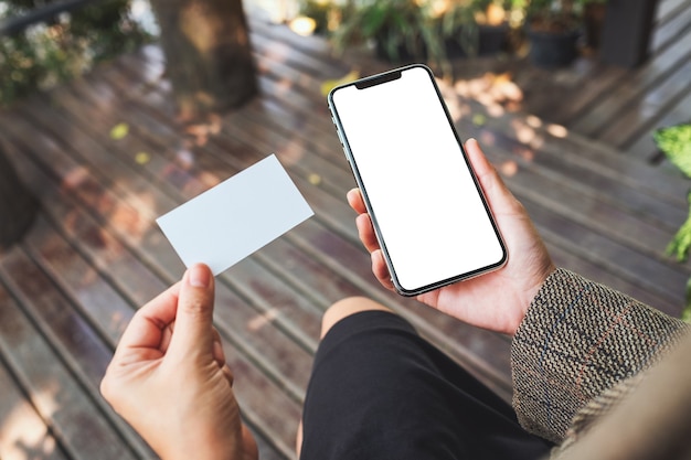 Mockup-afbeelding van een vrouw met een witte mobiele telefoon met een leeg desktopscherm en een wit leeg visitekaartje