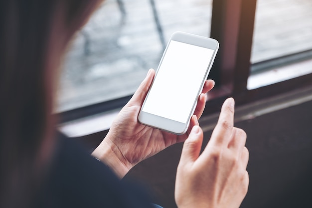 Mockup-afbeelding van een vrouw met een witte mobiele telefoon met een leeg desktopscherm in café