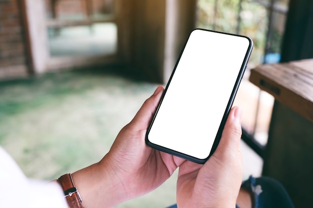 Mockup-afbeelding van een vrouw met een zwarte mobiele telefoon met een leeg desktopscherm terwijl ze in een café zit