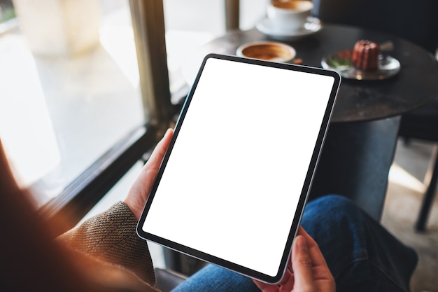 Mockup-afbeelding van een vrouw met zwarte tablet-pc met een leeg wit scherm in café