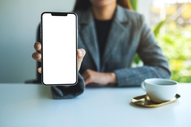 Mockup-afbeelding van een zakenvrouw die een mobiele telefoon vasthoudt en toont met een leeg wit scherm