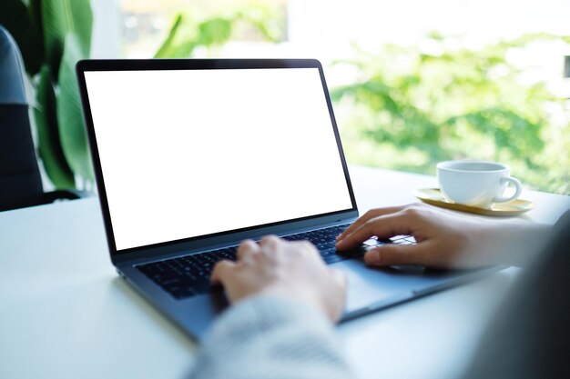 Mockup-afbeelding van een zakenvrouw die op het toetsenbord van de laptop met een leeg wit desktopscherm op kantoor typt en gebruikt