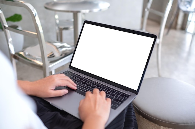 Mockup beeld van een vrouw die een laptop gebruikt en schrijft met een leeg wit desktop scherm