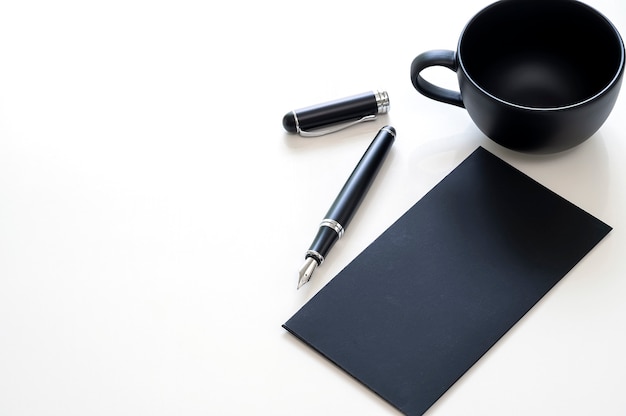 모형 검은 카드, 펜 및 복사 공간 흰색 테이블에 빈 컵.