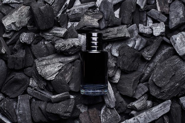 Mockup of black fragrance perfume bottle mockup on dark coals background. Top view. Horizontal