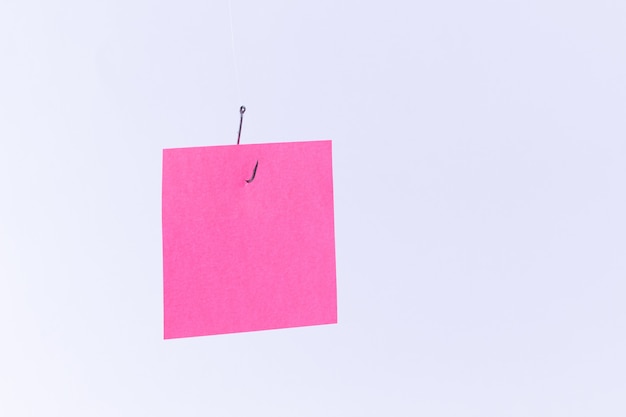 Mockup of a blank pink memo paper with copy space hanging on a fishing hook