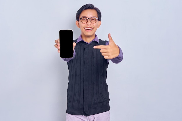 Mockup blank screen cellphone cheerful young asian man in
casual shirt showing mobile phone with blank screen recommending
mobile app isolated on white background people lifestyle
concept