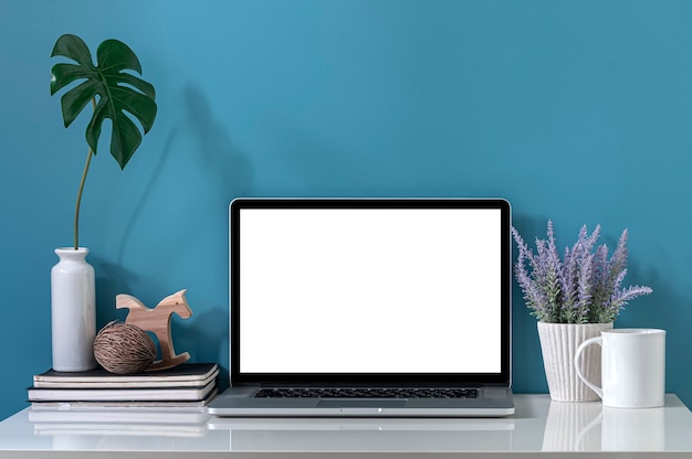 Mockup blank screen laptop computer on white top table and light blue wall.