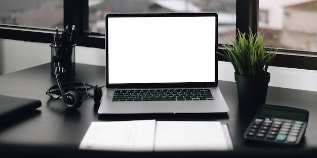 Mockup blank screen laptop and office supplies on white desk.