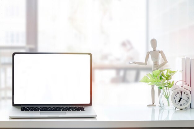 Computer portatile dello schermo in bianco del modello sulla tavola di legno bianca nello spazio co-working.