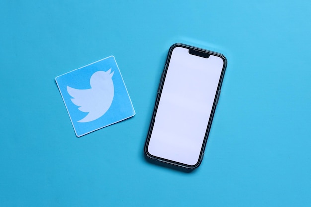A mockup of blank screen smartphone with printed paper of social media Twitter application logo isol