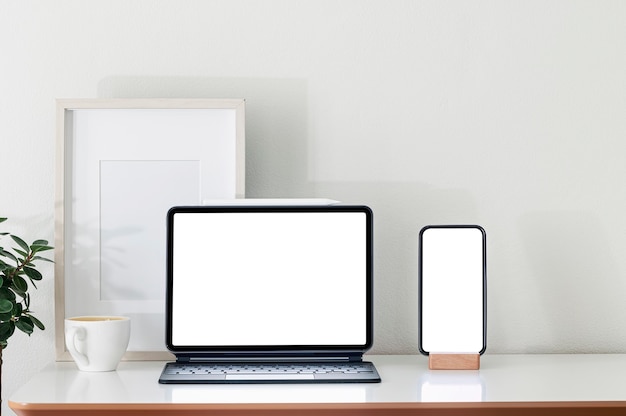 Photo mockup blank screen tablet with magic keyboard and smartphone on wooden table.