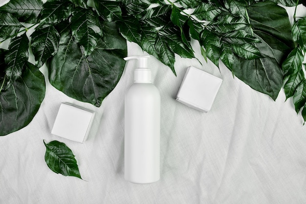 Mockup di bottiglia bianca vuota su foglie tropicali verdi, packaging cosmetico, vista dall'alto del tubo crema, composizione piatta