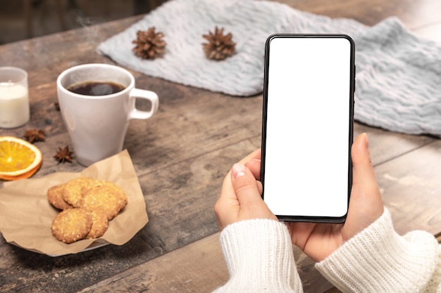 Mockup cellphone. Woman in a woolen sweater holds a cell phone mockup,