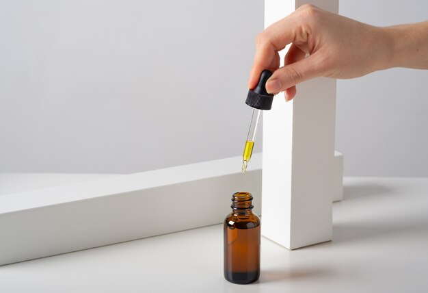 Siero cosmetico per il viso mockup, bottiglia di vetro marrone olio con una pipetta su uno sfondo bianco elegante e minimalista con decorazioni geometriche.