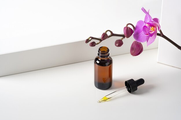 Mockup cosmetic face serum, oil brown glass bottle with a pipette on a stylish minimalist white background