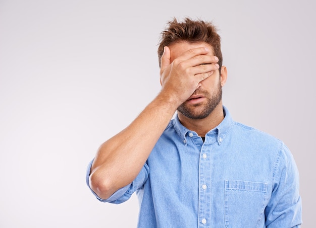 Mockup covering eyes and man with regret mistake and guy against a grey studio background Male person model or human with hand on face frustrated and problem with an issue upset or disappointed