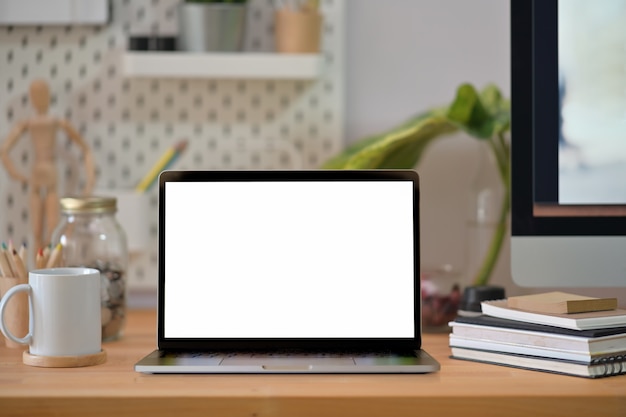 Mockup creative wood desk with blank screen laptop