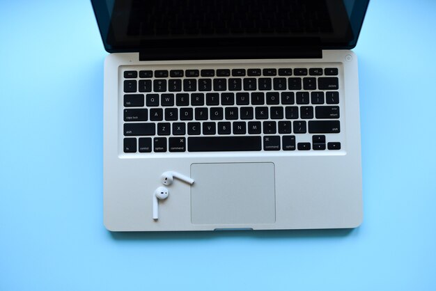 Mockup. de laptop en air pods op toetsenbord .blue tafel