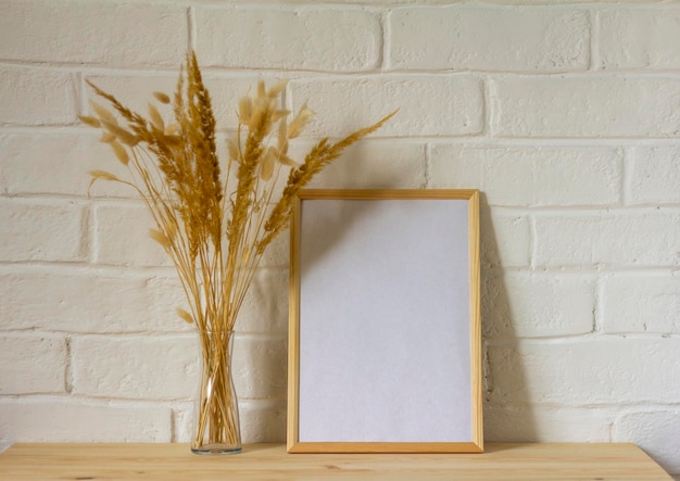 A mockup of an empty photo frame and an autumn bouquet of dried herbs