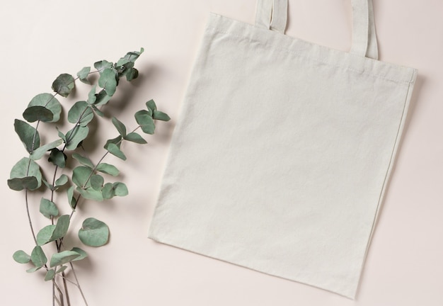 Mockup empty template White cream shopping bag for your design, eco friendly, zero waste with copy space. Eucalyptus branches. Flat lay.