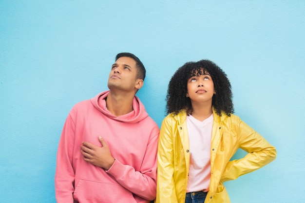 Foto mockup en mode denken met een zwart stel op een blauwe achtergrond in studio-branding of productplaatsing muurstijl en mock-up met een man en een vrouw die poseren op lege ruimte in trendy kleding