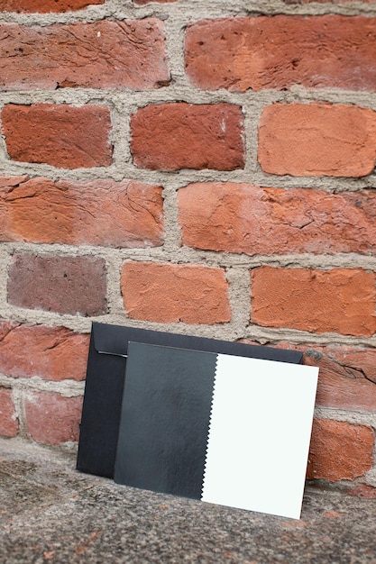 Фото Дружественный макет вертикального шаблона сертификата открытки с черным конвертом на кирпичной стене