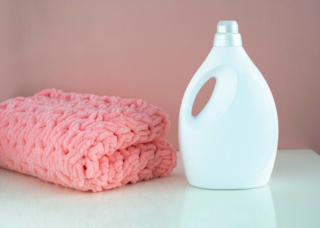 Mockup of a gel for washing woolen colored things on a pink\
background with a space for copying folded knitted blanket with air\
conditioning for washing and rinsing