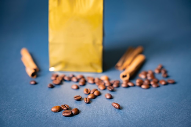 Mockup golden metallic paper pouch bag on a blue background lying at coffee beans with cinnamon