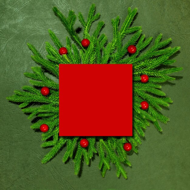 A mockup of green branches with a red paper card for the inscription New Year and Christmas Top view