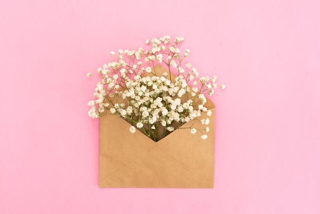 Mockup of gypsophila flowers in envelope on blue background top view in flat lay style