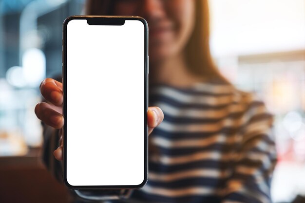 Foto immagine mockup di una bella donna asiatica che tiene e mostra un telefono cellulare con schermo bianco vuoto